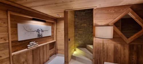 Intérieur rustique du chalet aux Chalets d'Aline avec foyer en pierre, équipements modernes et art contemporain