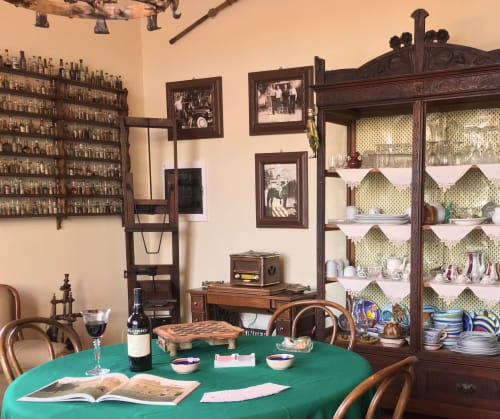 Sala da pranzo vintage dell'Hotel Candalú con tovaglia verde, bottiglia di vino, foto incorniciate, mobili in legno, vetrina