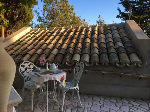 Affascinante terrazza giardino dell'Hotel Candalú con sedie bianche in stile vintage, tavolino e tetto rustico in coppi
