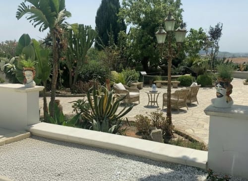 Cortile mediterraneo dell'Hotel Candalú con cactus, area relax, terrazza in pietra e vista sulla campagna di Valderice