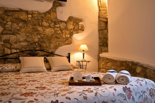 Suite rustica con muri in pietra al Candalú Hotel, letto, lampada, servizio caffè, asciugamani arrotolati e luce calda