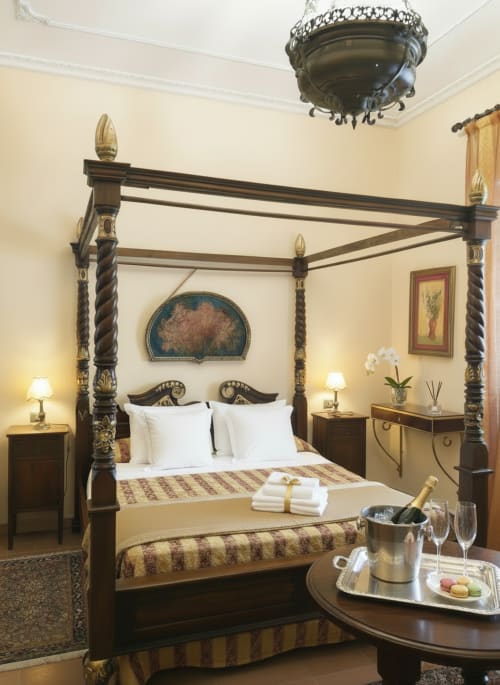 Suite con letto a baldacchino lussuoso al Candalú Hotel Villa Giardinata in Sicilia, eleganti arredi in legno scuro e vista sul giardino