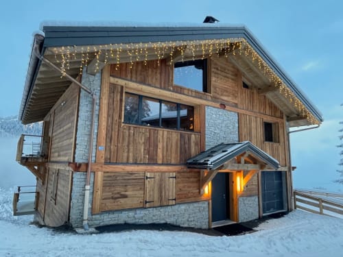 Chalet alpin moderne en bois avec détails en pierre, éclairage chaleureux et décoration festive aux Chalets d'Aline à La Plagne