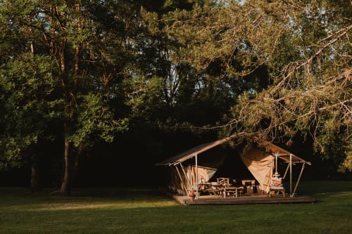 Tente safari aux gîtes de Cormenin avec mobilier extérieur et terrasse en bois donnant sur le jardin, entourée d'arbres