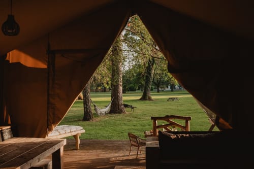 Intérieur de tente safari aux gîtes de Cormenin avec vue sur le jardin, terrasse en bois et espaces verts arborés