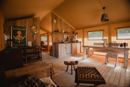Intérieur de tente safari aux Gîtes de Cormenin avec mobilier en bois, jeu d'échecs et vue sur le jardin