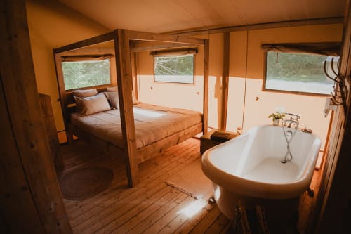 Intérieur luxueux de tente safari avec lit à baldaquin, baignoire îlot et vue sur le jardin aux gîtes de Cormenin, France
