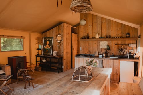 Intérieur de tente safari en bois aux gîtes de Cormenin avec table à manger, cuisine et vue sur le jardin
