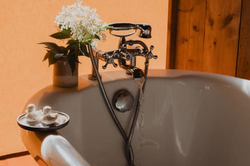 Baignoire vintage sur pieds avec robinetterie noire et fleurs blanches à l'hébergement Les gîtes de Cormenin en France