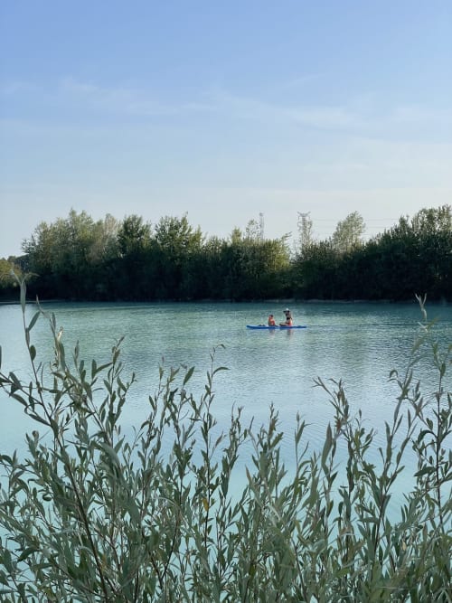 Deux personnes en kayak sur une eau turquoise, entourées de roseaux et d'arbres aux Gîtes de Cormenin