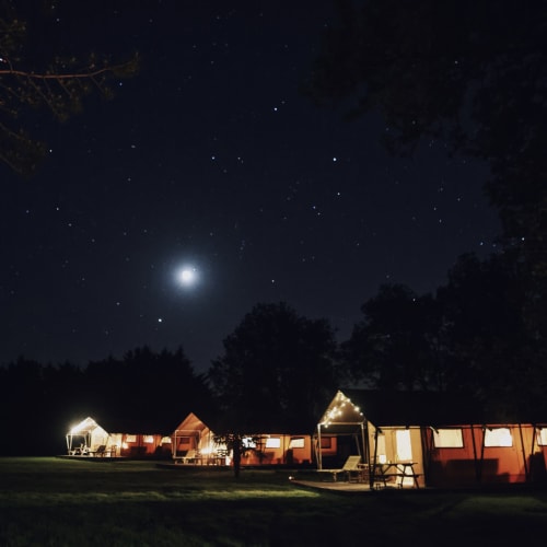 Tentes de safari illuminées des Gîtes de Cormenin sous la lumière lunaire et les étoiles, Saint-Hilaire-sur-Puiseaux