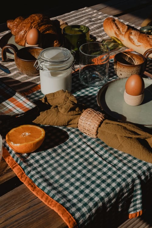 Petit-déjeuner rustique aux gîtes de Cormenin : croissants, œufs, pot de lait, orange et linge rayé sur table en bois