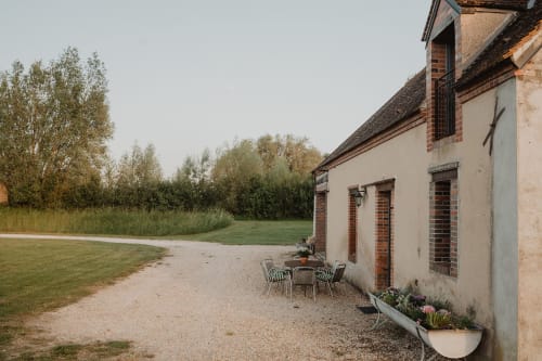 Terrasse rustique des gîtes de Cormenin avec salon de jardin, vue sur le jardin et architecture en brique