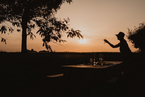 Silhouette d'une personne admirant le coucher de soleil au bord du lac à la villa Les gîtes de Cormenin avec espace de restauration extérieure