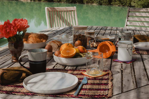 Table de petit-déjeuner en bord de lac aux gîtes de Cormenin avec fruits frais, pain et couverts face à la verdure