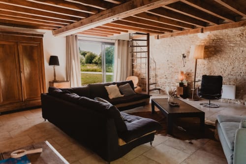 Spacieux séjour de villa avec canapés noirs, poutres apparentes, carrelage en terre cuite et vue sur le lac aux Gîtes de Cormenin