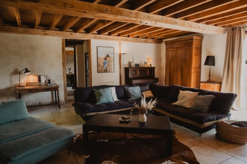 Spacieux séjour aux poutres apparentes, mobilier sombre et cheminée de la villa La Muzardière aux gîtes de Cormenin