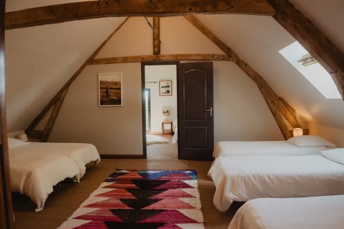 Chambre spacieuse sous les combles avec poutres apparentes aux Gîtes de Cormenin, deux lits et tapis coloré