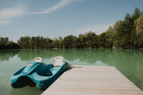 Kayaks turquoise sur ponton en bois, vue sur le lac vert tranquille des Gîtes de Cormenin