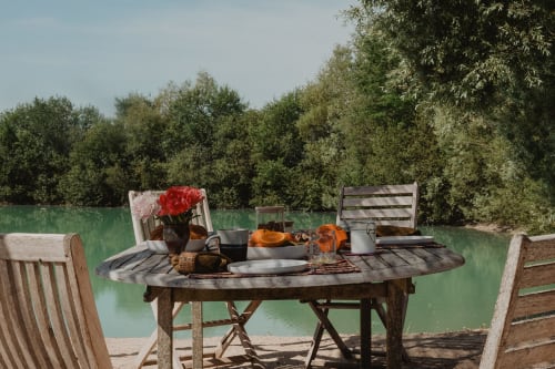 Mise en place pour dîner au bord du lac à la villa Les gîtes de Cormenin avec fleurs rouges, couverts et vue sur la forêt
