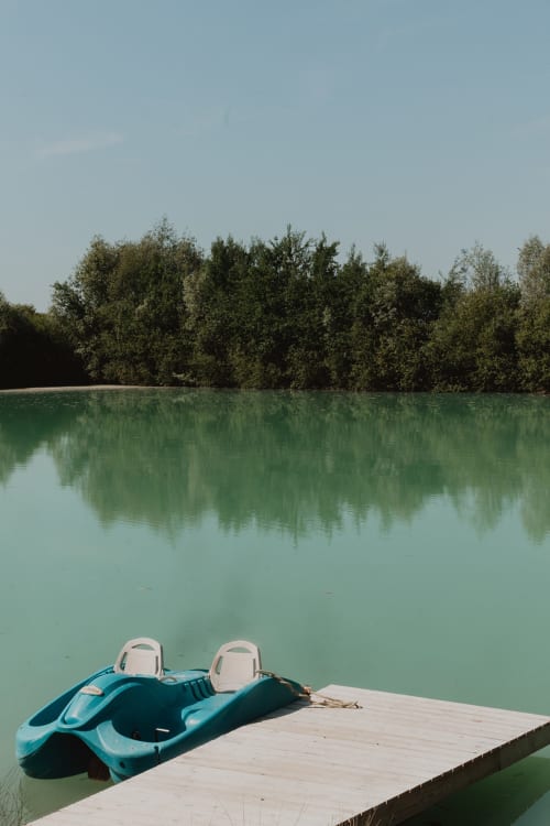 Kayak bleu amarré à l'embarcadère en bois avec lac turquoise et rive boisée aux gîtes de Cormenin