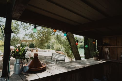 Terrasse couverte des gîtes de Cormenin avec vue sur le lac, guirlandes colorées, fleurs blanches et coin détente