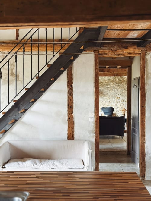 Chambre loft spacieuse aux poutres apparentes, escalier métallique, mobilier blanc et vue panoramique sur le lac aux Gîtes de Cormenin