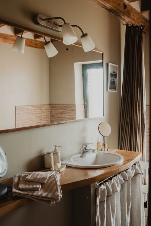 Salle de bain rustique avec meuble en bois, lavabo rond et miroir à la villa Les gîtes de Cormenin en France