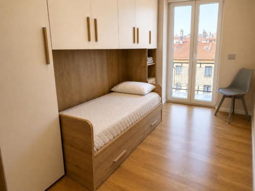 Camera moderna dell'appartamento TuffonelBlu a Sanremo con letto in legno, armadi bianchi, pavimenti in parquet e vista sulla città