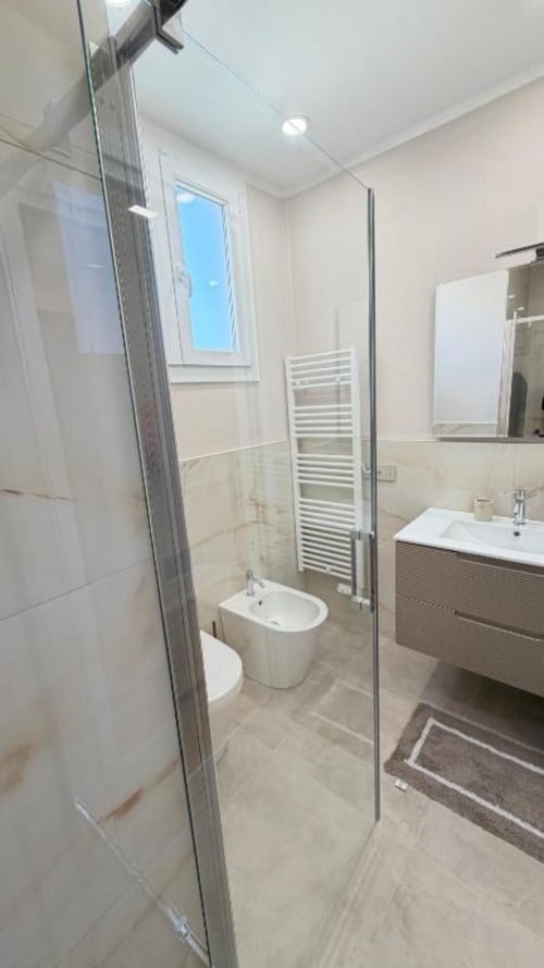 Bagno moderno nell'appartamento TuffonelBlu Sanremo con doccia a filo pavimento, doppio lavabo e vista oceano