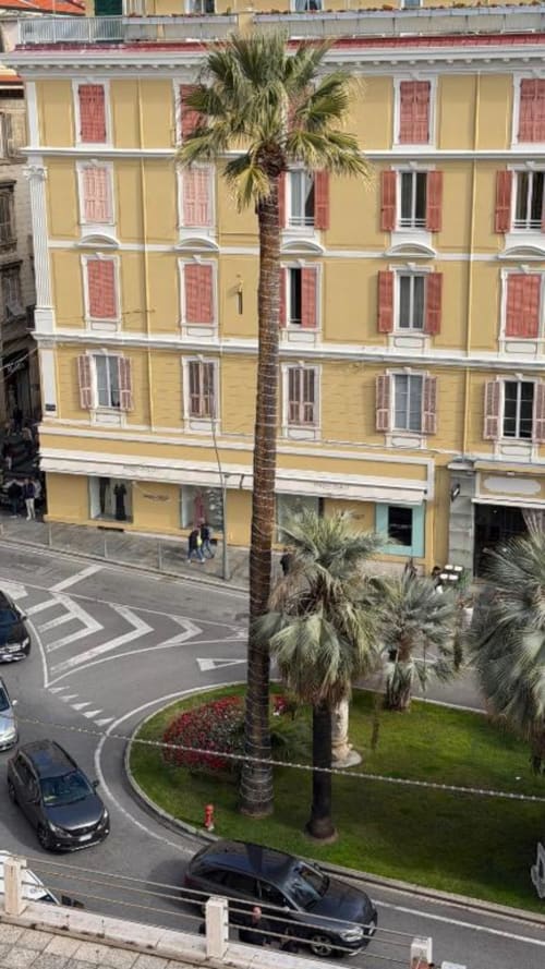 Balcone dell'appartamento TuffonelBlu con vista sulla strada di Sanremo, palme e edificio giallo in stile Haussmann