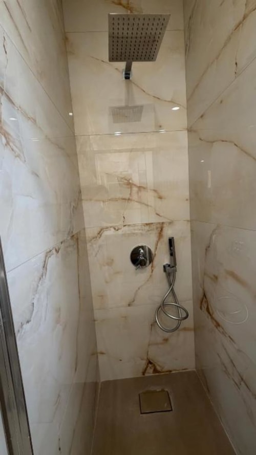 Moderno bagno nell'appartamento TuffonelBlu di Sanremo, con soffione pioggia, rivestimenti effetto marmo e design contemporaneo