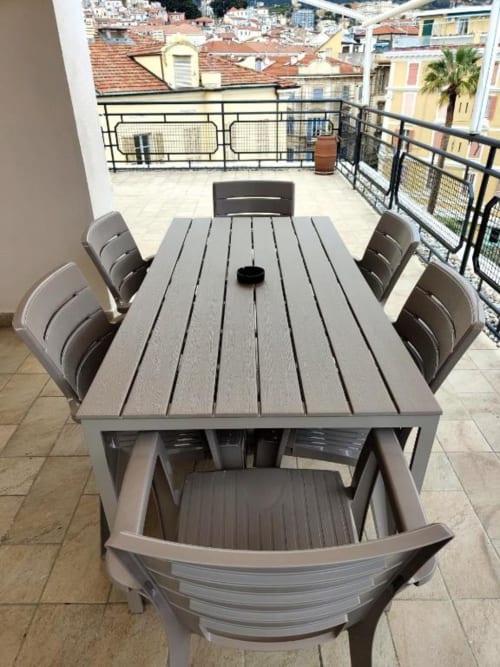 Zona pranzo in terrazza dell'appartamento TuffonelBlu a Sanremo con tavolo grigio, sedie e vista panoramica sulla città