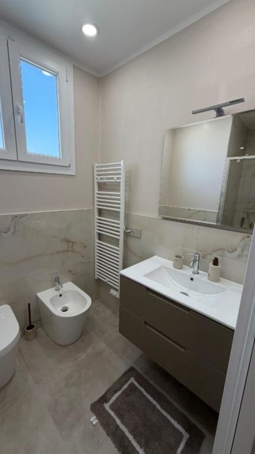 Bagno moderno nell'appartamento TuffonelBlu a Sanremo con doppi lavabi, scaldasalviette e vista finestra