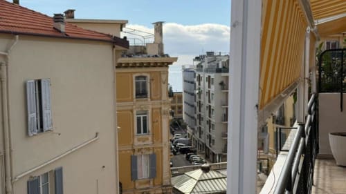 Balcone dell'appartamento a Sanremo con tenda gialla a righe affacciato su vie e edifici cittadini, Attico Matteotti