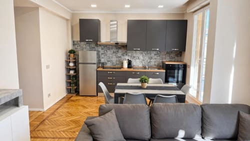 Cucina open-plan moderna e soggiorno dell'Attico Matteotti di TuffonelBlu a Sanremo con mobili scuri e vista mare