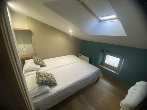 Chambre mansardée moderne à AJOUCADOU Lourmarin avec lit queen-size, puits de lumière, mur accent vert et équipements contemporains