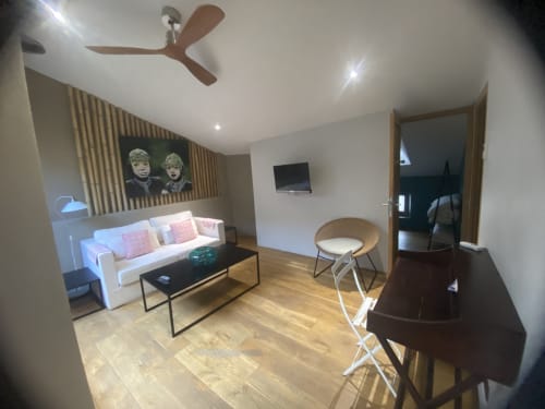 Salon moderne de l'appartement AJOUCADOU à Lourmarin avec canapé blanc, télévision, parquet et ventilateur de plafond