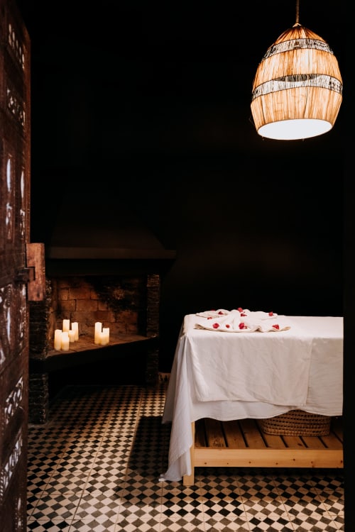 Chambre romantique à l'hôtel Eucalyptus Ethnic à Essaouira avec luminaire suspendu tissé, bougies et lit drapé de blanc
