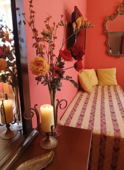 Camera della suite con pareti color corallo presso l'Hotel Candalú, con fiori freschi, cuscini gialli e biancheria a righe a Valderice, Sicilia