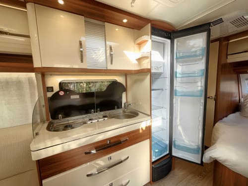 Cocina moderna de autocaravana con estufa, fregadero y refrigerador abierto en alojamiento El Pla Del Penedès