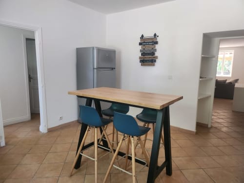 Modern kitchen dining area at Domaine De Poulharies with wooden table, blue bar stools, and stainless steel refrigerator