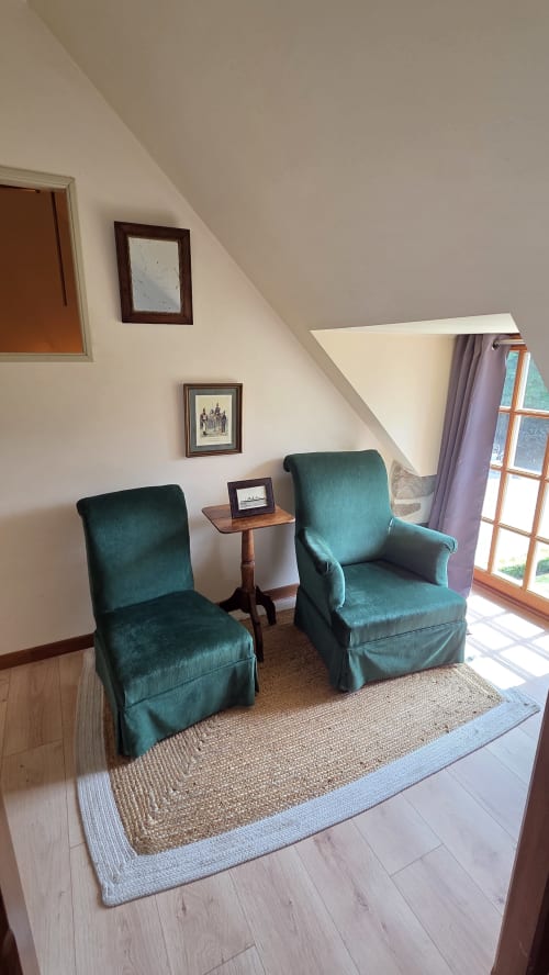 Cozy attic seating area with two teal armchairs at Manoir de la Bégaudière, Mont-Dol, featuring garden views and sloped