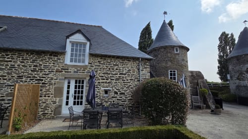 Stone manor garden courtyard at Manoir de la Bégaudière, Mont-Dol, with seating area and tower turrets