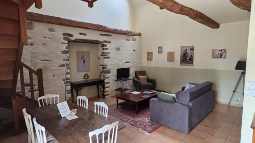 Manoir de la Bégaudière apartment Le Surcouf: rustic living room with fireplace, dining table, and garden view