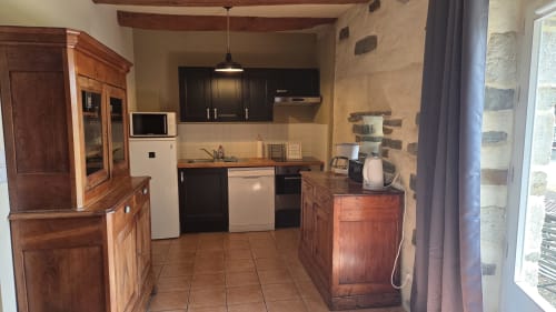 Kitchen with wooden cabinetry, black countertops, and stainless appliances at Manoir de la Bégaudière, Mont-Dol