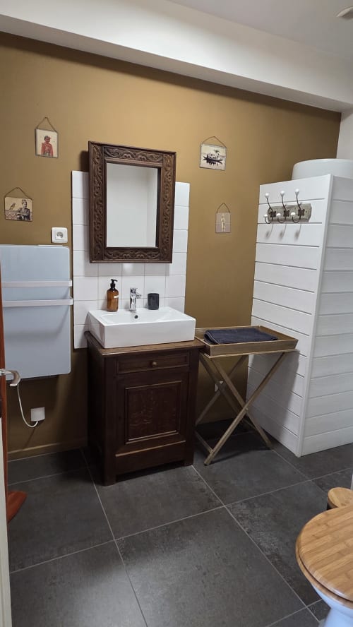 Bathroom in Le Chateaubriand at Manoir de la Bégaudière with sink, ornate mirror, and ochre walls
