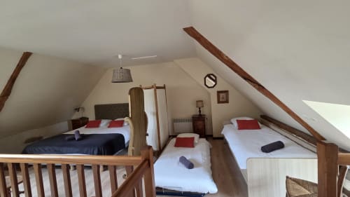 Le Chateaubriand bedroom at Manoir de la Bégaudière, Mont-Dol: attic room with exposed beams, multiple beds with white