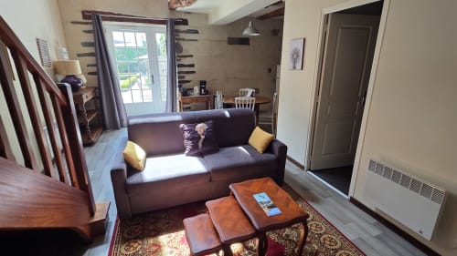 Cozy living room with dark sofa, wooden coffee table, and garden views at Manoir de la Bégaudière in Mont-Dol