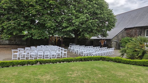 Outdoor wedding ceremony setup with white chairs in garden at Manoir de la Bégaudière, Mont-Dol